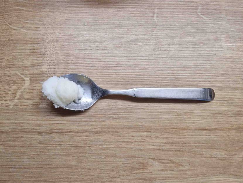 Ein Teelöffel mit getesteter Sheabutter liegt auf einer Holzoberfläche.
