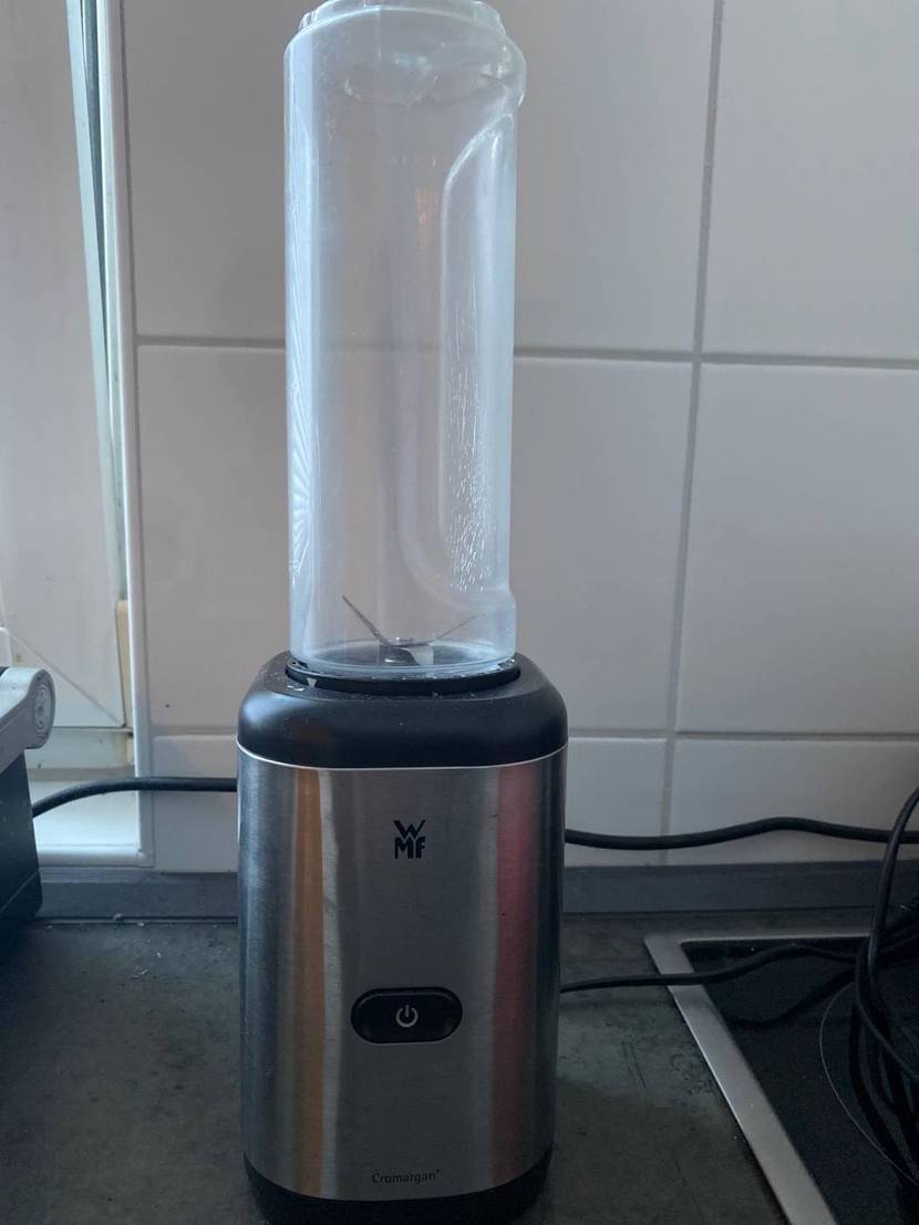 Standmixer-Test: ein Edelstahl-Modell von WMF inklusive Kunststoff-Zerkleinerungsbehälter steht auf einer grauen Arbeitsplatte.
