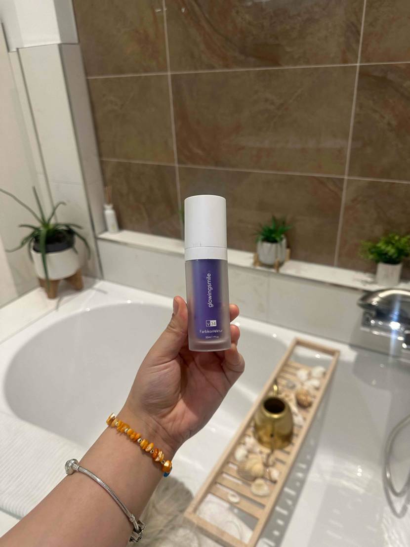 Eine Hand hält einen Flakon mit Zahnaufhellung zum Testen über eine Badewanne.